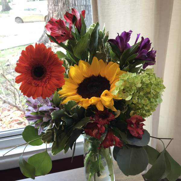 Mixed bouquet with sunflowers, gerbera daisies, and alstroemeria in a glass vase