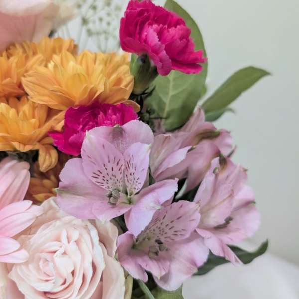 Bouquet of pink, peach, and magenta flowers with green leaves