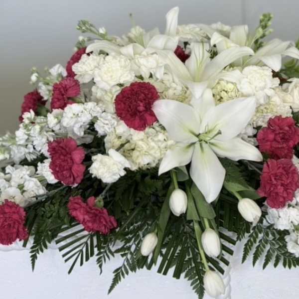 White lilies and pink carnations arranged in a casket spray