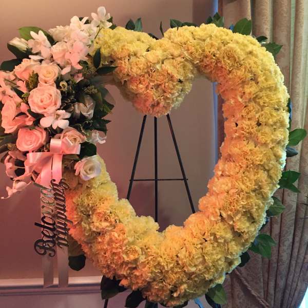 Heart-shaped floral wreath with pink roses and yellow carnations