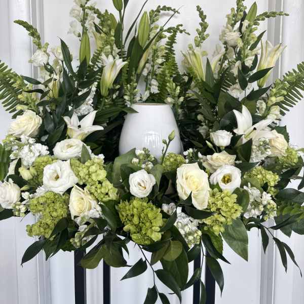 White floral arrangement with lilies, roses, and green hydrangeas in a vase