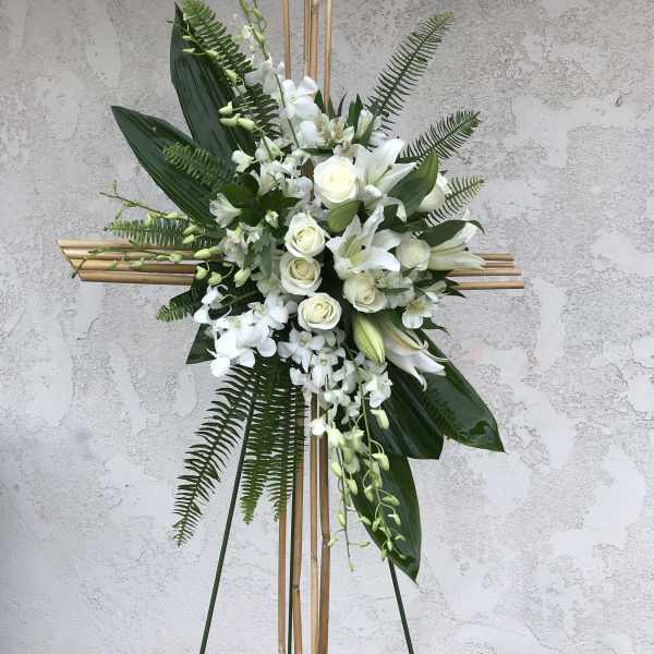 White floral standing spray on a bamboo cross frame
