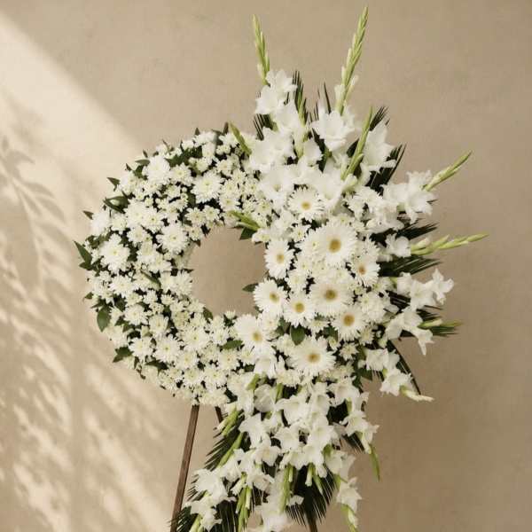 White floral funeral wreath on a stand with daisies and lilies