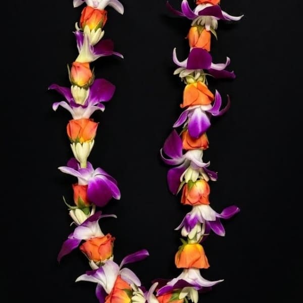 A floral lei made of orange, purple, and white blossoms on a black background