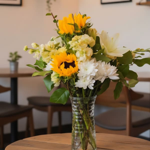 Bouquet of yellow sunflowers and white flowers in a clear glass vase