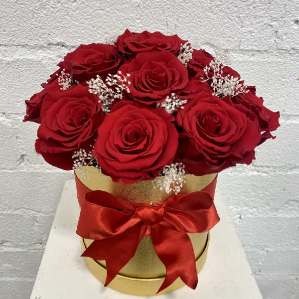 Red roses in a gold box with a red ribbon