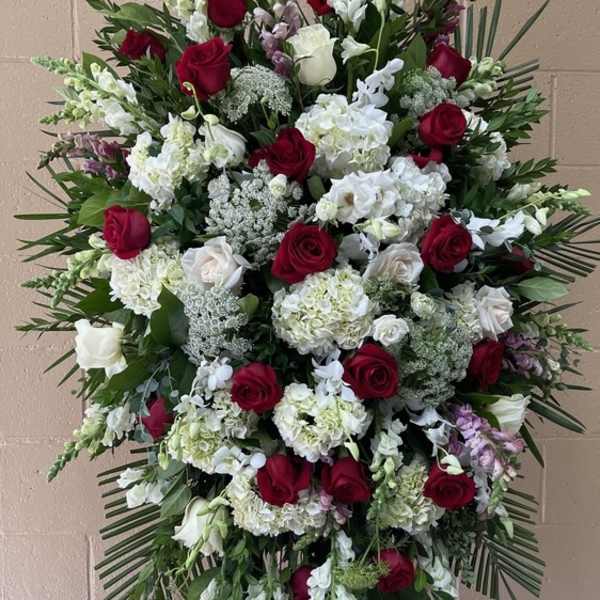 Standing spray of red and white roses with mixed white blooms