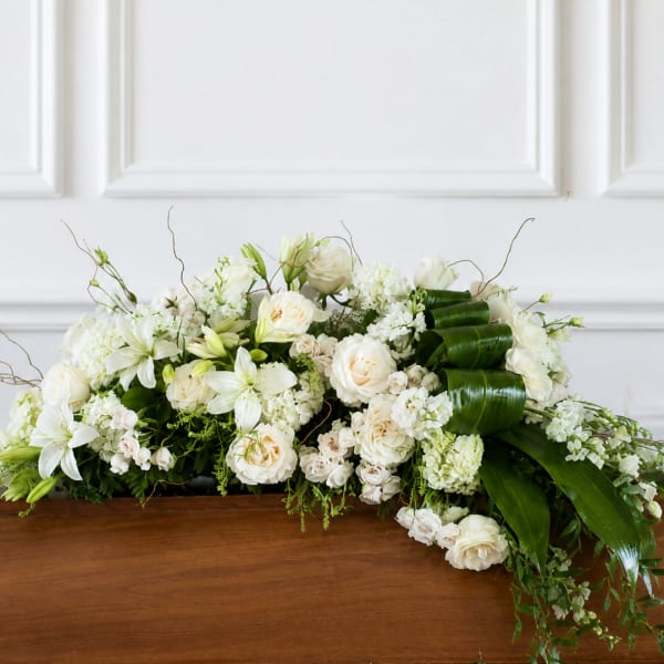 White floral casket spray with roses and lilies