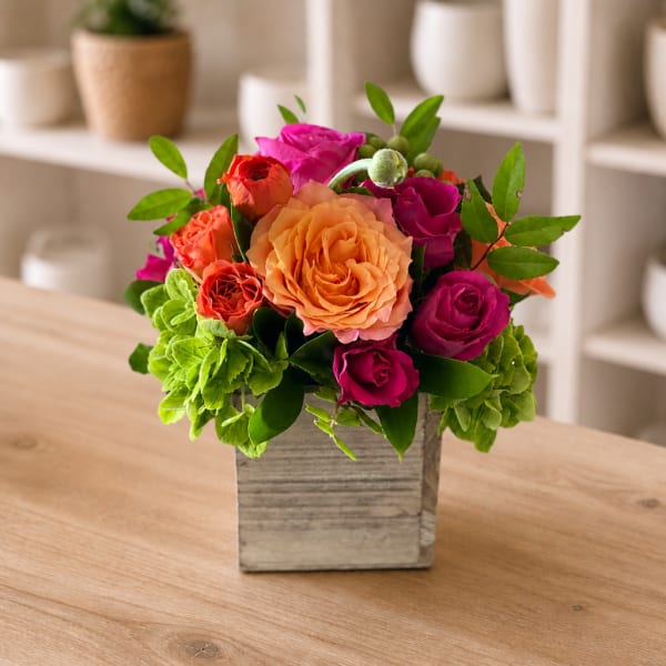 Colorful rose arrangement in a square wooden vase on a table