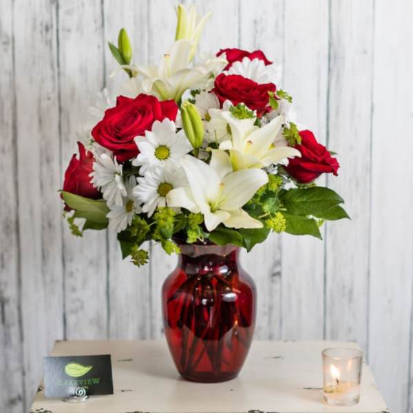 Red roses and white lilies in a red glass vase