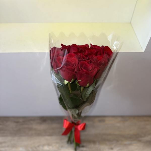 Bouquet of red roses wrapped in clear plastic with a red ribbon