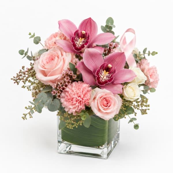 Pink orchids and roses arranged in a clear square vase