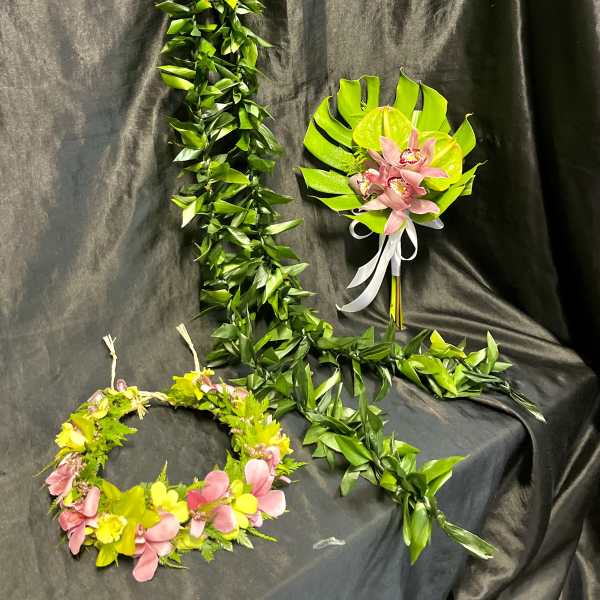 Two floral leis and a pink orchid bouquet on a dark draped background.