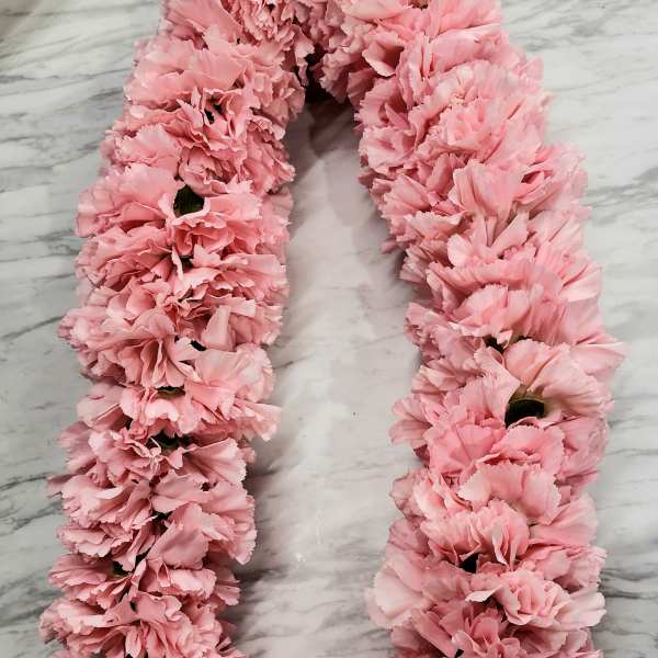Pink carnation lei with a white ribbon bow
