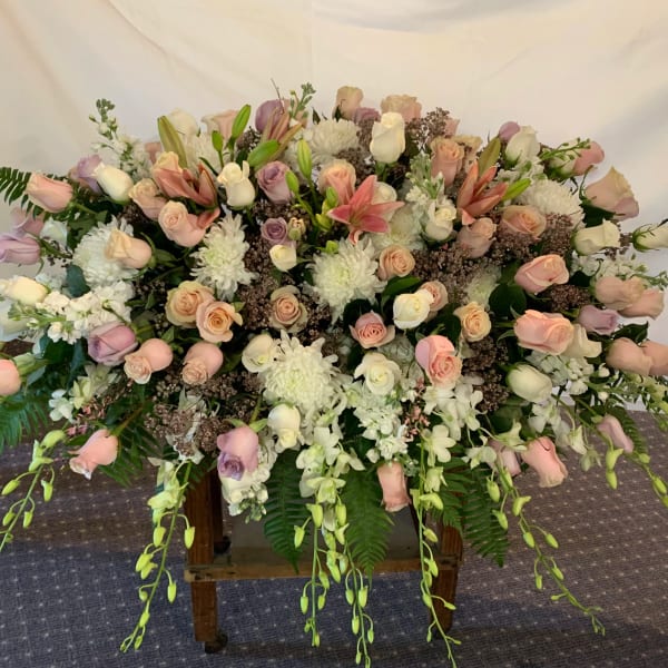 Large pastel floral spray with roses, lilies, and white blooms on a stand