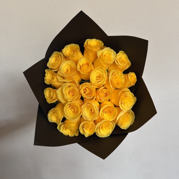 Bouquet of yellow roses wrapped in dark paper