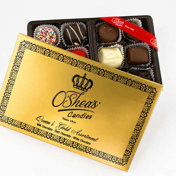 Box of assorted chocolates in a gold gift box with the lid partly open.