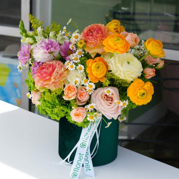 Colorful mixed bouquet in a dark green hatbox with ribbon