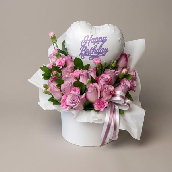 Pink roses and carnations in a white hat box with a birthday balloon