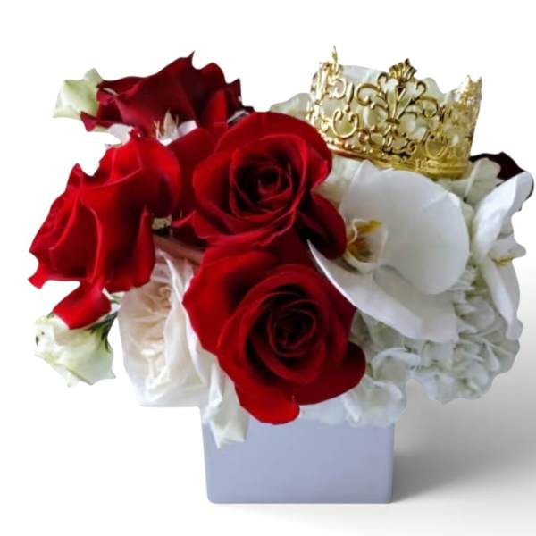 Red and white rose arrangement with a gold crown in a white vase
