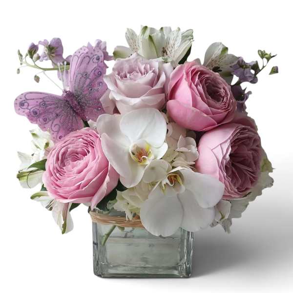 Pink and white flower arrangement in a square glass vase with a purple butterfly decoration