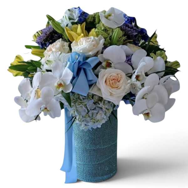 Bouquet of white orchids, roses, and mixed blooms in a blue-wrapped vase