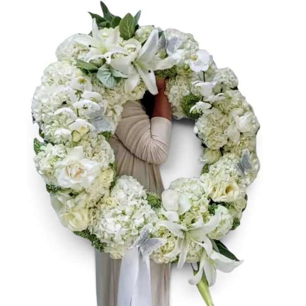 Large white floral wreath with lilies and roses around a person