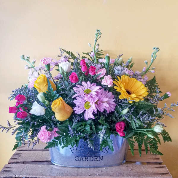Mixed bouquet in a metal container with pink, yellow, white, and lavender flowers