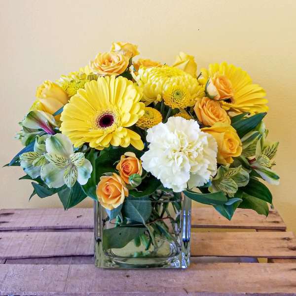 Yellow and white mixed bouquet in a square glass vase