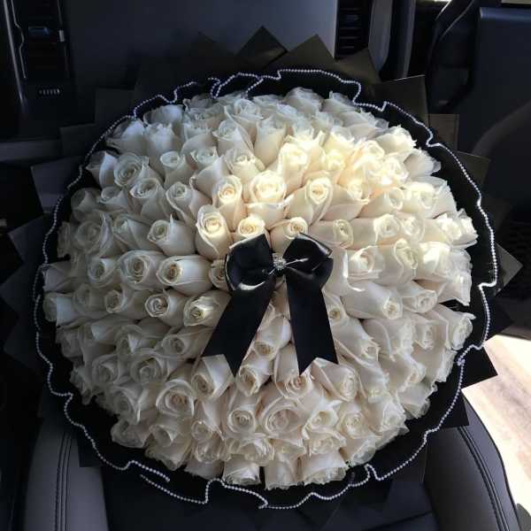 Large bouquet of white roses wrapped in black paper with a black ribbon
