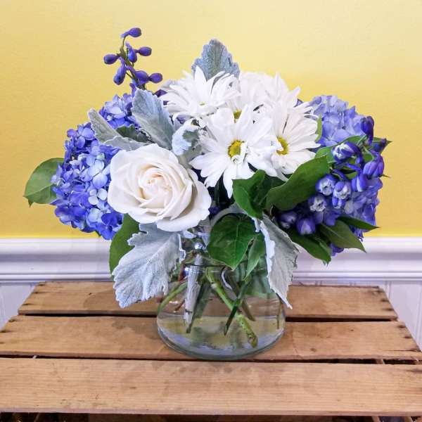 Blue and white flowers arranged in a clear glass vase