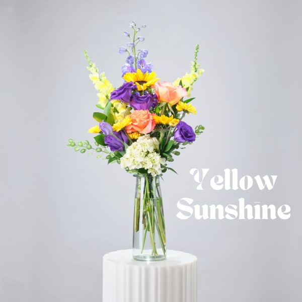 Mixed bouquet in a glass vase with sunflowers, roses, and purple blooms