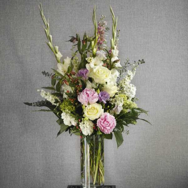 Tall floral arrangement in a clear glass vase with pink, white, and lavender blooms