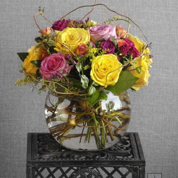 Mixed roses in a clear glass vase with curly branches