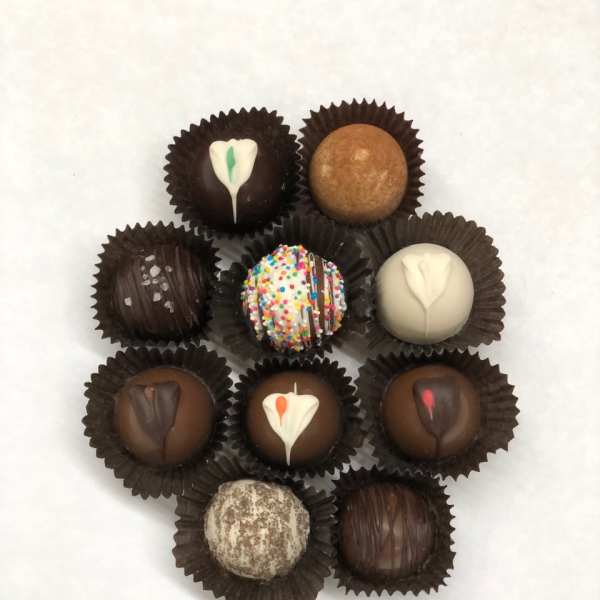 Assorted chocolate truffles with varied toppings arranged in a circle on a white background