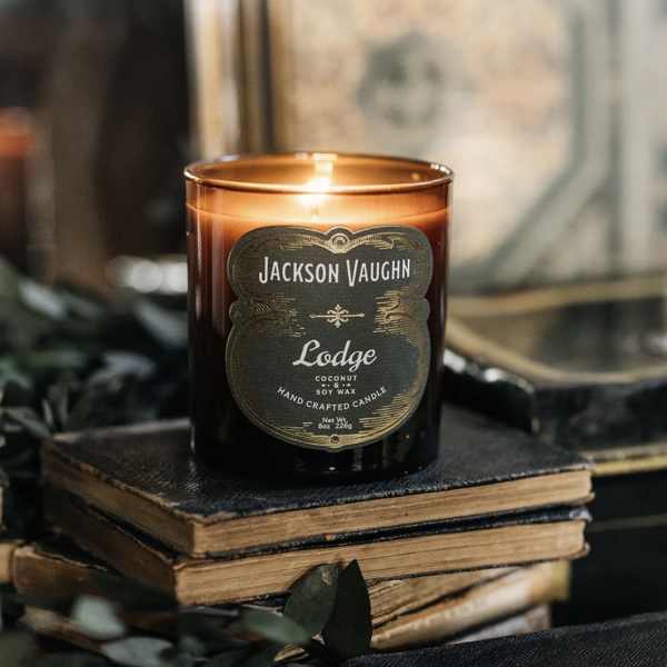 Lit amber candle in a glass jar on stacked books
