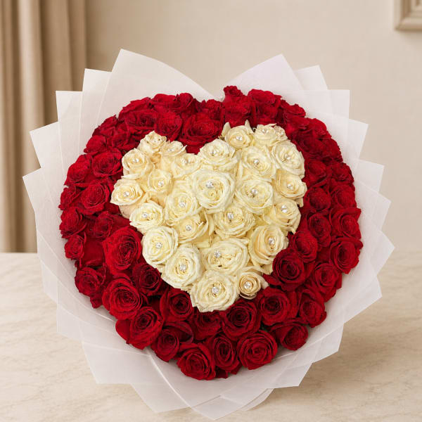 Heart-shaped bouquet of red and cream roses wrapped in white paper