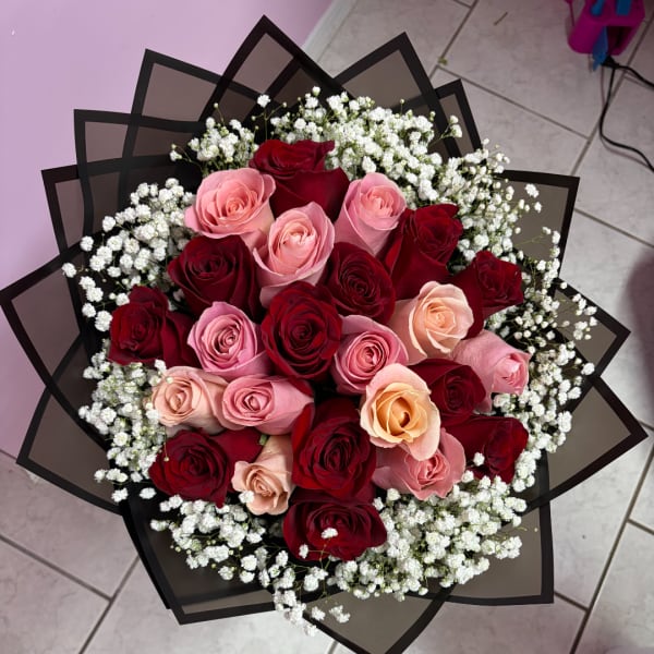 Bouquet of red and pink roses with white baby's breath in black wrap