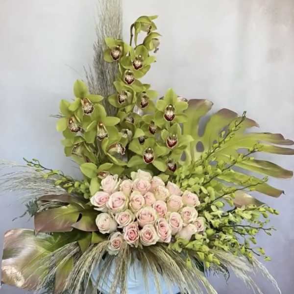 Tall floral arrangement with pale pink roses and green orchids in a vase