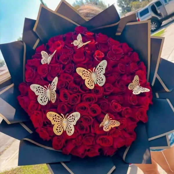 Round bouquet of red roses with decorative butterfly accents.