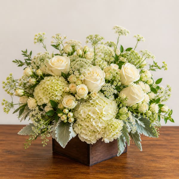 Cream roses and hydrangeas arranged in a wooden box