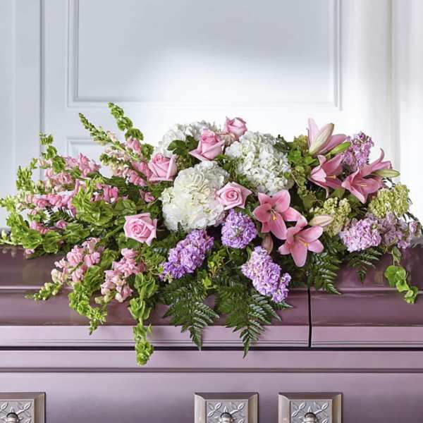 Pink and white floral casket spray with lilies, roses, and hydrangeas