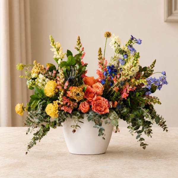 Colorful mixed flower arrangement in a white pot