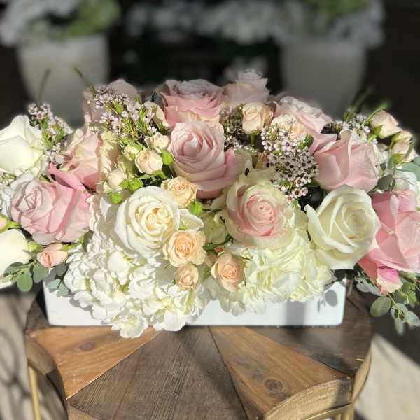 Pink and white roses arranged in a low white container