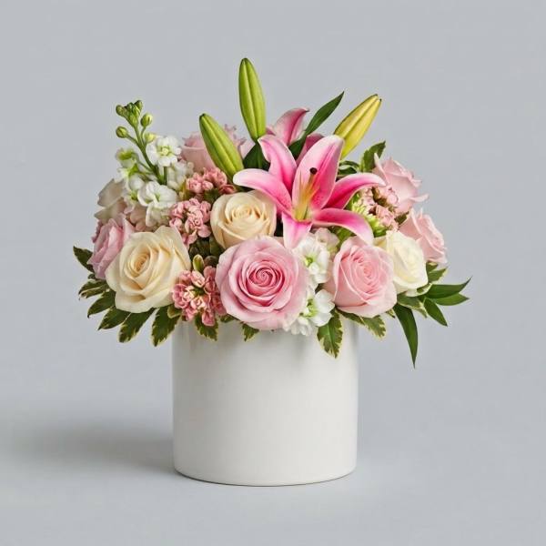 Pink and cream roses with lilies in a white vase
