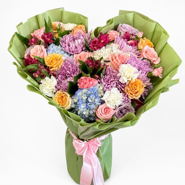 Mixed bouquet of roses, chrysanthemums, hydrangeas, and carnations wrapped in green paper