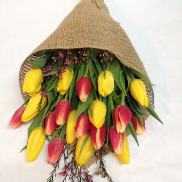 Bouquet of yellow and pink tulips wrapped in burlap