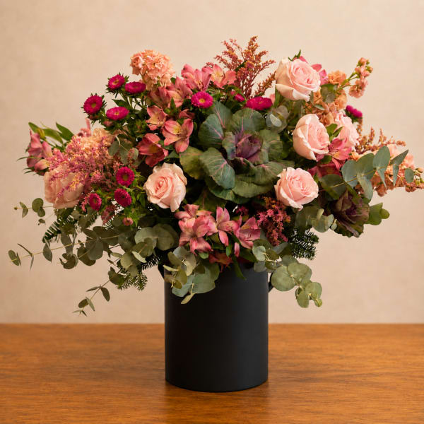 Pink and peach floral arrangement in a black vase