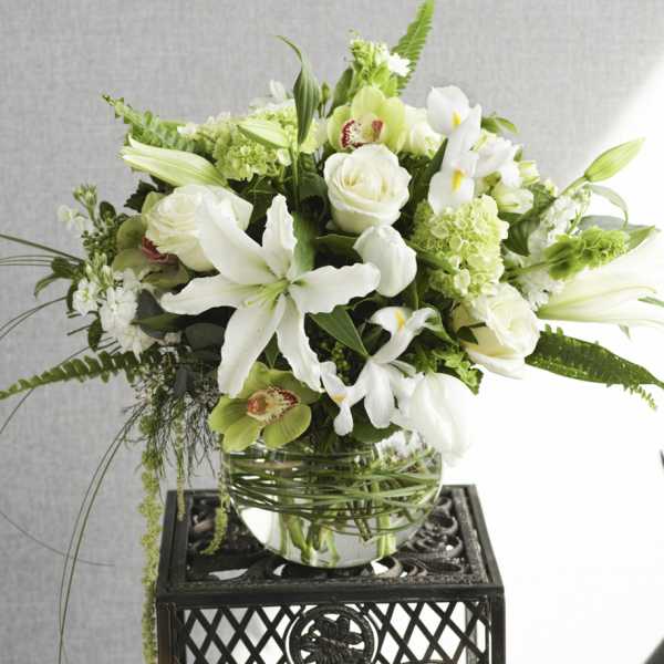 White and green floral arrangement in a glass bowl vase