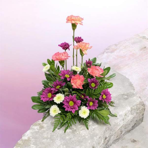 Pink and purple flower arrangement with white blooms on a rock